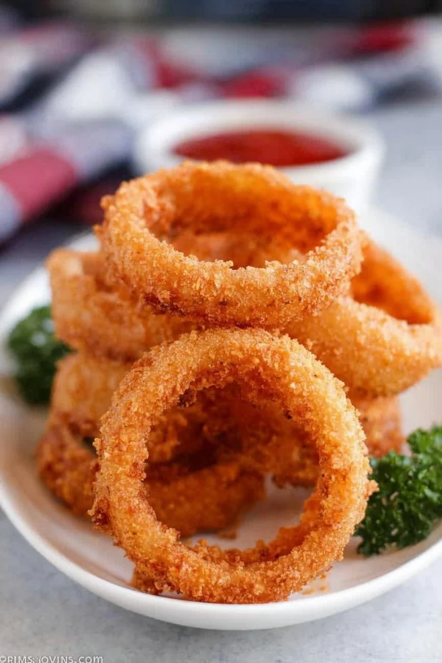 Golden, crispy Deep Fried Onion Rings piled high on a plate