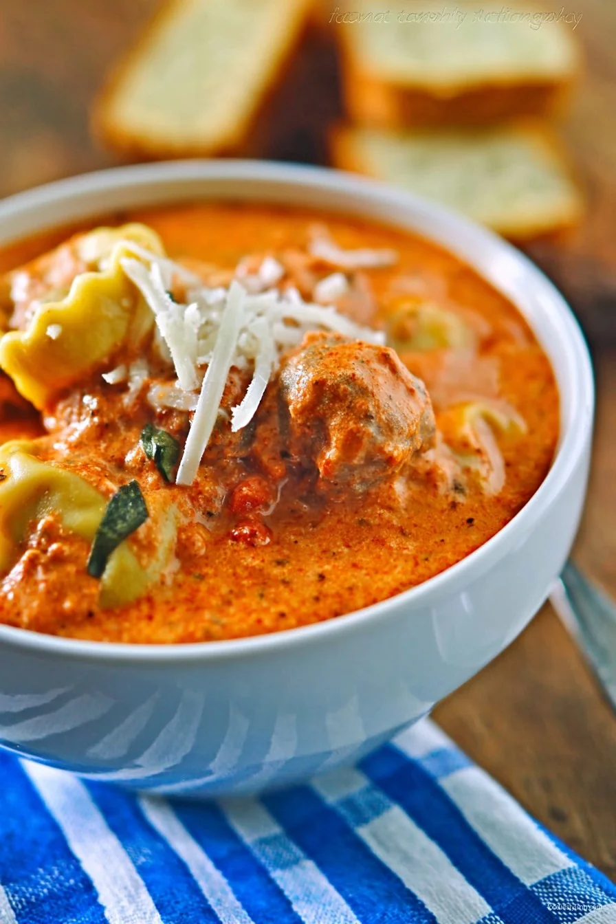 A steaming bowl of Tuscan Ravioli Soup topped with fresh basil and Parmesan